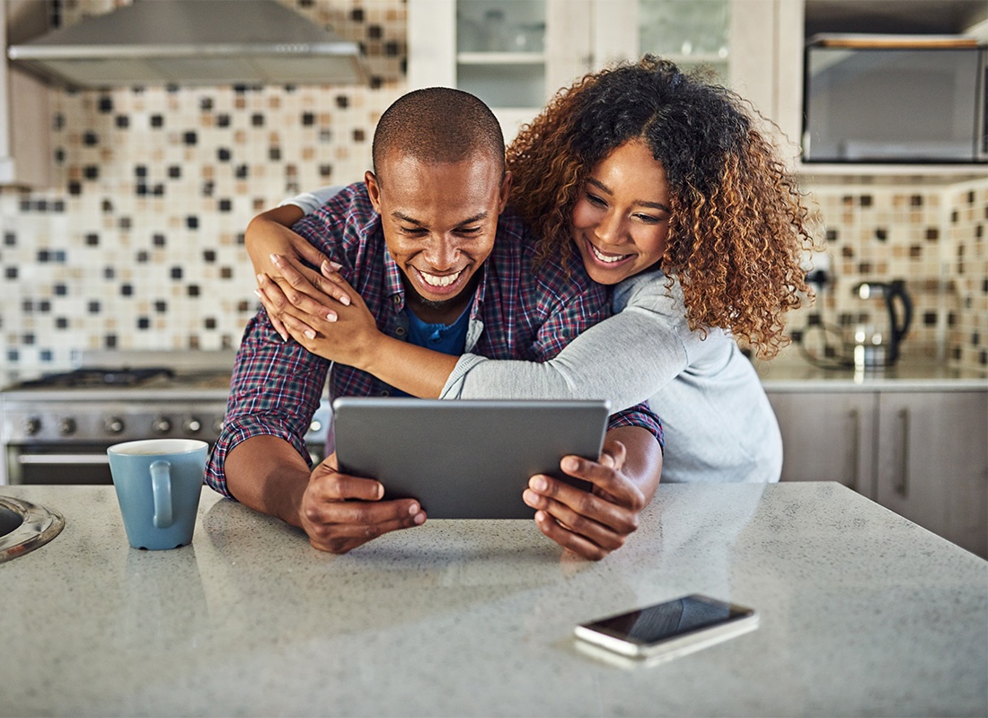 Blog - Closeup View of a Young Cheerful Married Couple Using a Tablet While Standing in Their Kitchen in the Morning